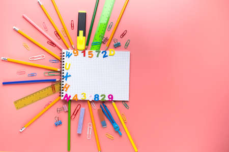 Many different school supplies and empty notepad white sheet of paper on pink copy space background. Back to school concept.の写真素材
