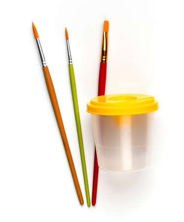 Plastic yellow cup for water to clean brushes while painting with watercolor paints.の写真素材