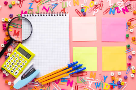 Many different school supplies and empty notepad white sheet of paper on copy space background. Back...