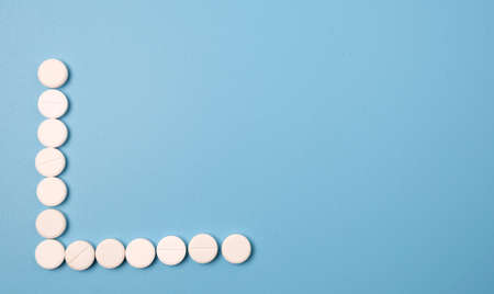 Close up of many white pills on blue background.