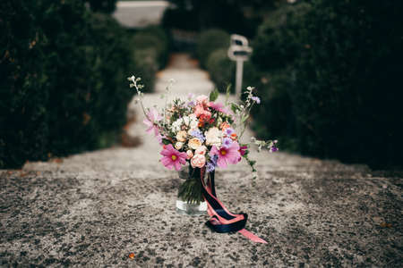 Bright wedding bouquet with peonies and wildflowers with pink ribbon, flowers in a vase in the parkの写真素材