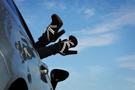 woman holds her feet from the car windowの写真素材