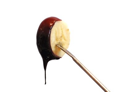 Fresh banana with dark chocolate sauce dripping from it の写真素材