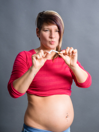 Pregnant woman breaking a cigarette - stop smoking conceptの写真素材