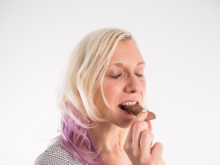 Picture of hungry young woman eating chocolateの写真素材