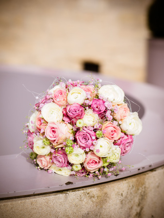 the bouquet of pink, pink and cream roses lies on the well in the sunの写真素材