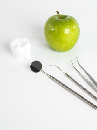 Green apple, tooth and dental tools isolated on whiteの写真素材