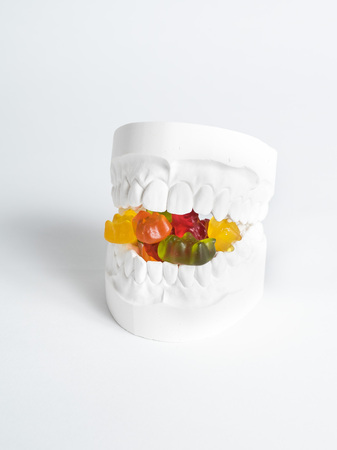The plaster bit has gummy bears between its teeth against a white background