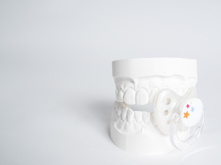Minimizing the malocclusion caused by pacifiers, the gypsum tooth with the pacifier in front of the...
