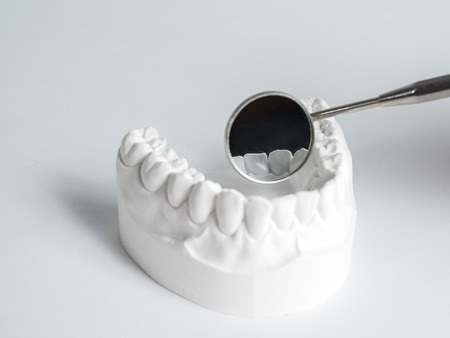 Teeth and dental mirror, symbol photo of dentures, diagnosis and copayment, on the white background