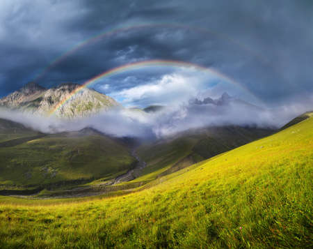 Rainbow in mountain valley during sunset. Beautiful natural landscapeの写真素材