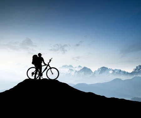 Silhouette of a bike tourist on mountain peak. Active life conceptの写真素材