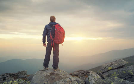 Tourist on the peak of high rocks. Sport and active life concept