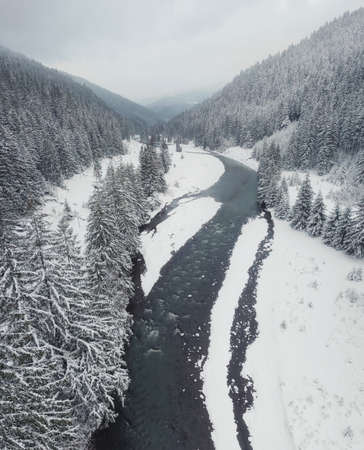 Winter landscape from air. Forest and river in the winter mountain valleyの写真素材
