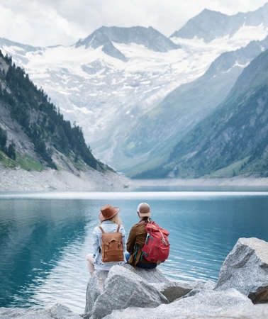 Travelers couple look at the mountain lake. Travel and active life concept with team. Adventure and travel in the mountains region in the Austriaの写真素材