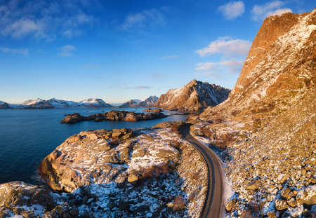 Aerial view at the road in mountains. Mountains and ocean shore during sunset in the Norway....