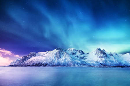 Aurora borealis on the Lofoten islands, Norway. Green northern lights above mountains. Night winter landscape with aurora and reflection on the water surface. Norway-imageの写真素材