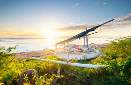 Boat on seashore during the sunrise. Sky and reflections on the water in the summer. Sun rays during...