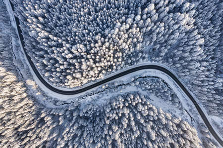 Aerial view on the road and forest at the winter time. Natural winter landscape from air. Forest under snow at the winter time. Winter travel - imageの写真素材