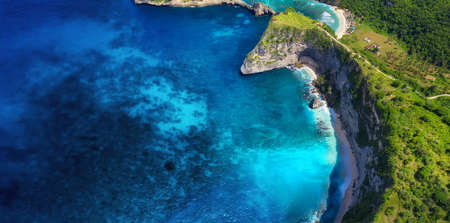 Aerial view at sea and rocks. Blue water background from top view. Summer seascape from air. Nusa...