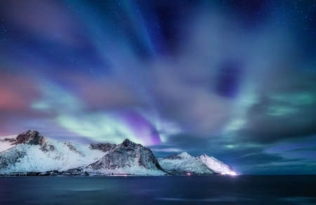 Aurora Borealis in Norway. Green northern lights above mountains and ocean. Night winter landscape with aurora. Natural phenomenon background in Norway.の写真素材