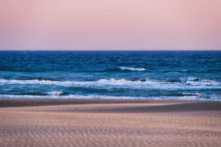 Sand dunes and seashore during sunset. Summer landscape in the desert. Hot weather. Lines in the sand. Landscape without people.の写真素材