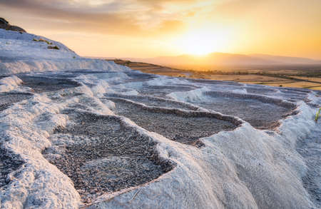 Summer landscape during sunset. The view of the travertines and the bright sunset. Calcium terraces without water. A popular place for tourism. White rocks and sunset. Pamukale, Turkey.の写真素材