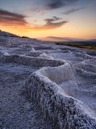 Summer landscape during sunset. The view of the travertines and the bright sunset. Calcium terraces without water. A popular place for tourism. White rocks and sunset. Pamukale, Turkey.の写真素材