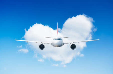 An airplane against a heart of clouds. A blue sky and a heart sign. Travel composition. High...
