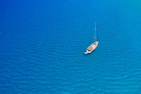 An aerial view of the yacht on the azure sea. Transparent clear water in the Mediterranean Sea. Summer vacations and travels on a sailing yacht. Summer relaxation.の写真素材