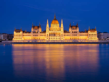 Parliament building in Budapest, Hungary. Parliament and reflections in the Danube River. Blue hour and evening illumination of the building. High resolution photo.の写真素材