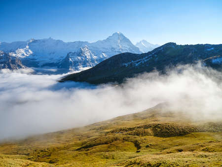 Mountains and clouds in the valley. Natural landscape high in the mountains. Mountain range through the clouds. Landscape in the summertime. Large resolution photo for design.の写真素材