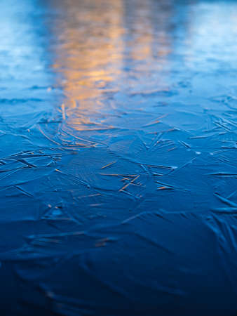 A frozen lake and reflections on the surface. Mountains during dawn. Abstract background. Detail in nature. High-resolution photo.の写真素材