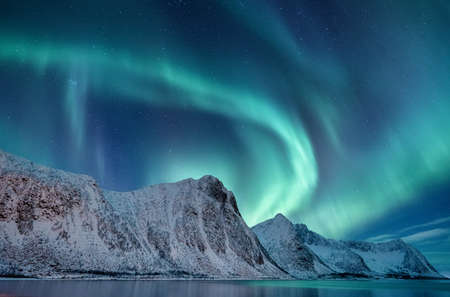 Aurora borealis in Norway. Green northern lights above mountains. Night winter landscape with aurora. Natural phenomenon background in Norway.の写真素材