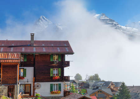 A village in Switzerland. A sunny day and a mountain valley. Houses against a mountain backdrop. High resolution photograph.の写真素材