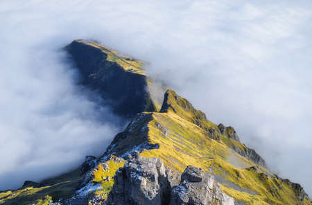 Mountains and clouds in the valley. Natural landscape high in the mountains. Mountain range through the clouds. Large resolution photo for design.の写真素材
