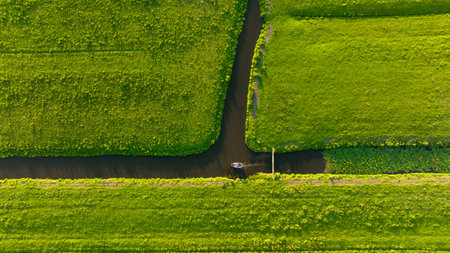 Aerial view of a canal boat in the Netherlands. Canals with water for agriculture. Fields and meadows. Landscape from a drone.の写真素材
