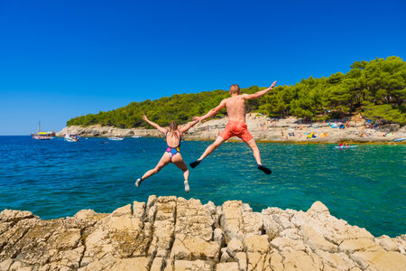 A carefree couple jumps into the azure sea. A vacation in the summertime. Young and energetic people dive into the water together. A fun vacation at the sea together.の写真素材