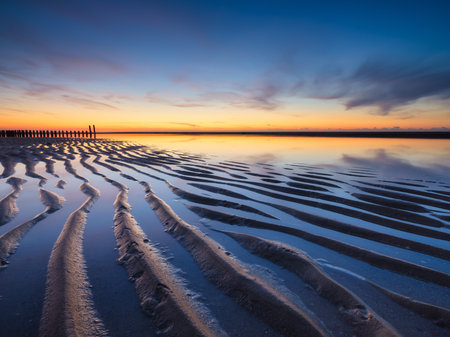 A seascape during sunset. Lines of sand on the seashore. Bright sky during sunset. A sandy beach at low tide. Travel image. Photography for design.の写真素材