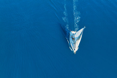 An aerial view of the sail yacht on the blue sea. Transparent clear water in the sea. Summer vacations and travels on a sailing yacht. Summer relaxation.の写真素材