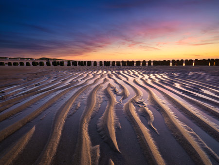 A seascape during sunset. Lines of sand on the seashore. Bright sky during sunset. A sandy beach at low tide. Travel image.の写真素材