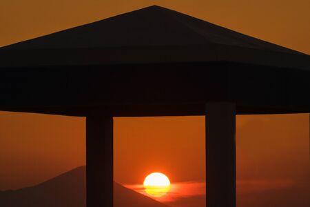 Sunset at Kalamos village in Greece. Sun is framed through the columns of a building.の写真素材