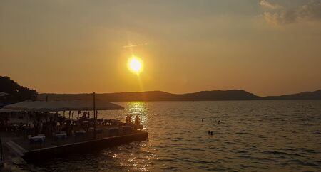 Sunset at Pilos in Greece. Silhouettes of local people and tourists.のeditorial素材