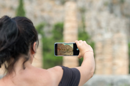 Woman taking a photo at the sanctuary of Apollo at Delphi area in Greece. A famous touristic destination.の写真素材