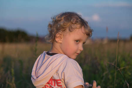 little boy in a field turns backの写真素材