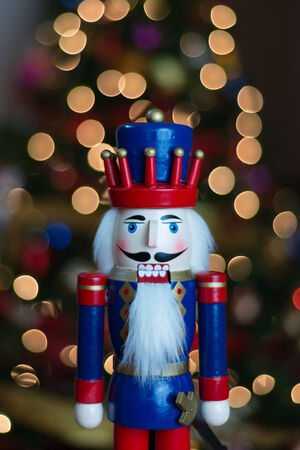 This is a colorful nutcracker in front of a Christmas tree.
