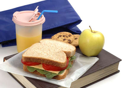 School lunch of sandwich, juice and snacks on a textbook.の写真素材