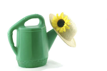 Green watering can and a straw hat.の写真素材