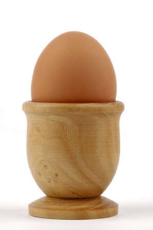 Brown egg sitting in a wooden egg cup.