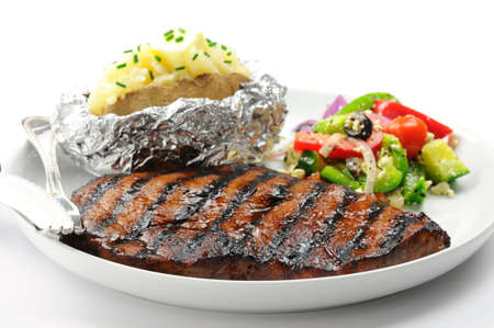 Grilled steak with baked potatoes and salad.の写真素材